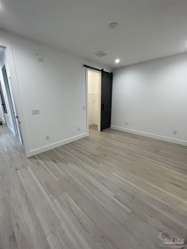 unfurnished room featuring light hardwood / wood-style floors and a barn door