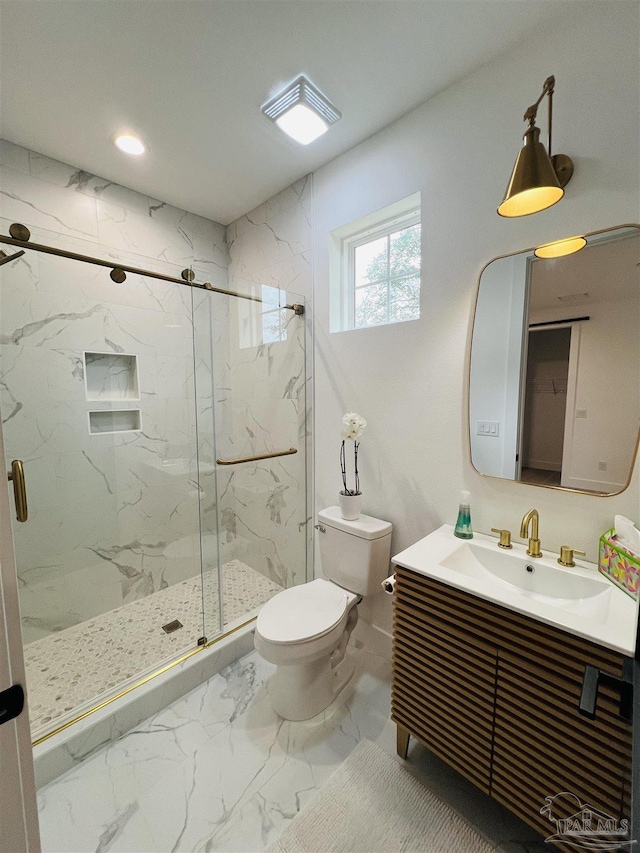 bathroom featuring toilet, marble finish floor, a marble finish shower, and vanity