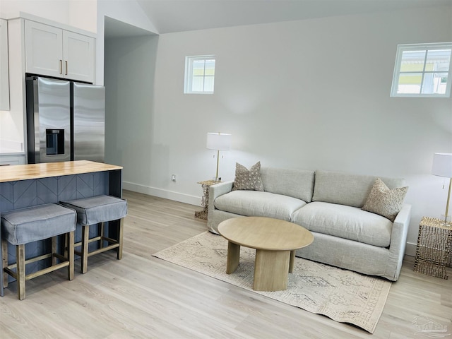 living area featuring baseboards, lofted ceiling, and light wood-style floors