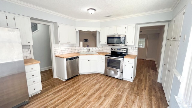 2708 Willow Grove Ln, Ft Walton Beach, FL 32547 - kitchen featuring appliances with stainless steel finishes, butcher block counters, a sink, tasteful backsplash, and ornamental molding