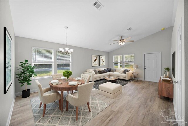 dining room featuring lofted ceiling, light wood-type flooring, and ceiling fan with notable chandelier