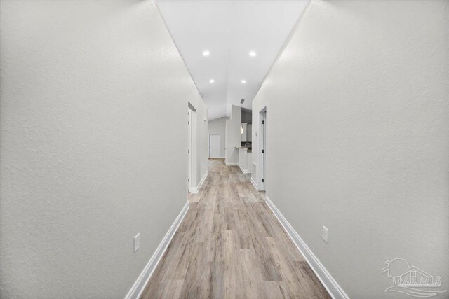 corridor featuring lofted ceiling and light hardwood / wood-style floors