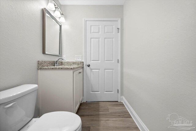 bathroom featuring toilet, vanity, and wood-type flooring