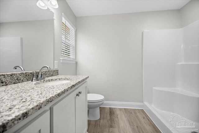 bathroom featuring vanity, hardwood / wood-style flooring, toilet, and walk in shower