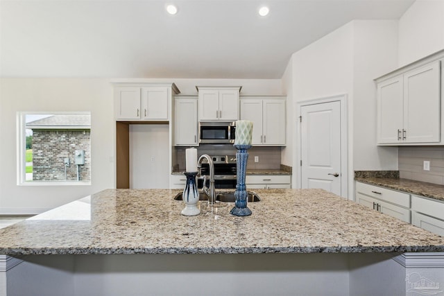 3975 Morning Dew Dr, Milton, FL 32583 - kitchen featuring a sink, light stone counters, stainless steel microwave, and a center island with sink