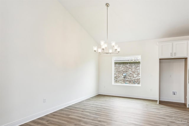 unfurnished dining area with baseboards, a notable chandelier, lofted ceiling, and light wood-style floors