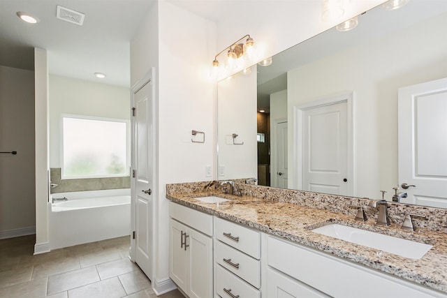 full bath with double vanity, tile patterned floors, a sink, and a bath