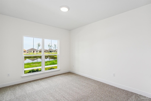 unfurnished room with carpet floors, baseboards, and a water view