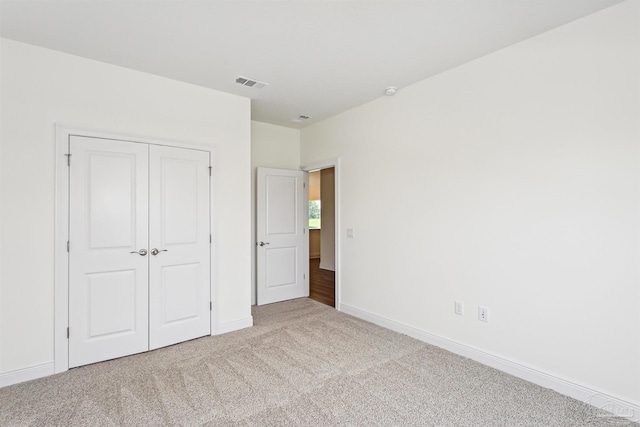 unfurnished bedroom featuring baseboards, visible vents, carpet, and a closet
