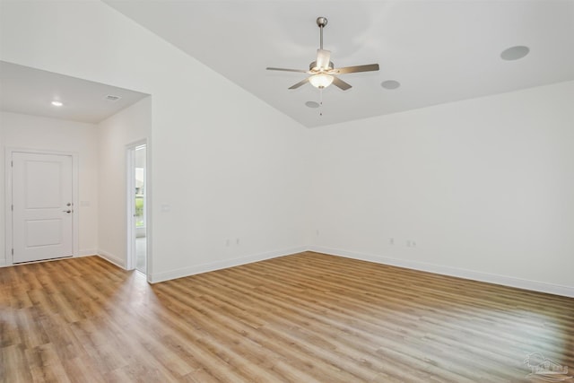 spare room with light wood-type flooring, a ceiling fan, baseboards, and vaulted ceiling
