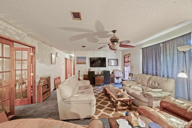 carpeted living room featuring ceiling fan and a textured ceiling