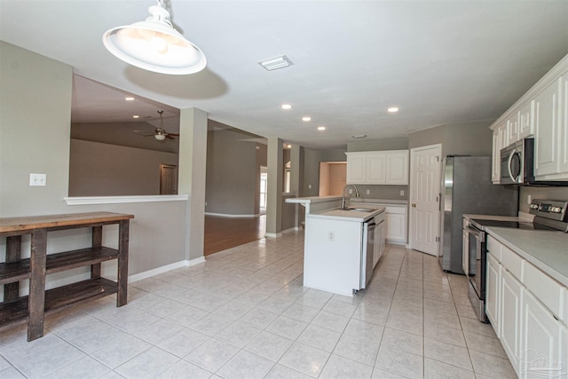 kitchen featuring ceiling fan, appliances with stainless steel finishes, white cabinetry, a kitchen island with sink, and vaulted ceiling