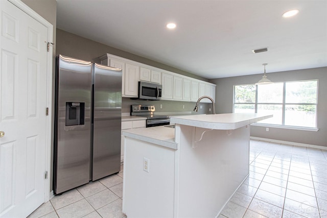 kitchen featuring white cabinetry, appliances with stainless steel finishes, light tile patterned floors, and a kitchen island with sink