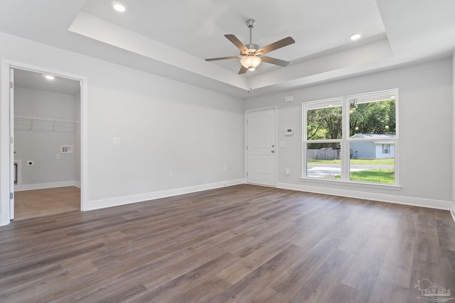 spare room with a tray ceiling, ceiling fan, and dark hardwood / wood-style floors