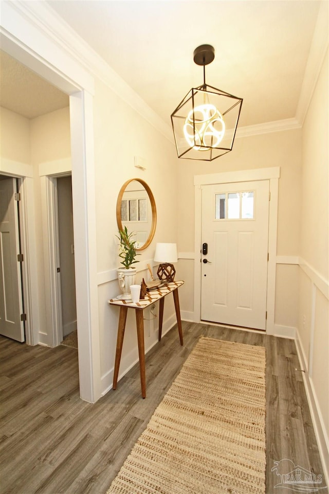 foyer with a wainscoted wall, crown molding, and wood finished floors