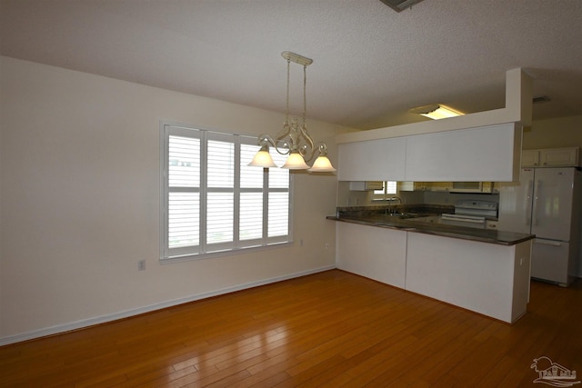 5577 Shadow Shore Pl, Gulf Breeze, FL 32563 - kitchen with white appliances, dark countertops, a peninsula, wood finished floors, and a textured ceiling