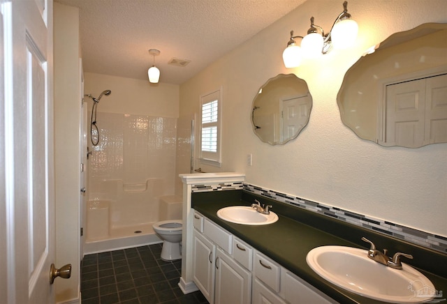 5577 Shadow Shore Pl, Gulf Breeze, FL 32563 - bathroom featuring walk in shower, a textured ceiling, toilet, tile patterned flooring, and double vanity