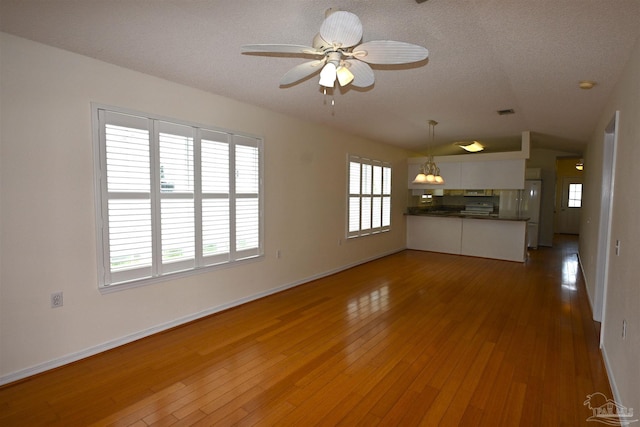 5577 Shadow Shore Pl, Gulf Breeze, FL 32563 - unfurnished living room featuring hardwood / wood-style flooring, a ceiling fan, baseboards, vaulted ceiling, and a textured ceiling