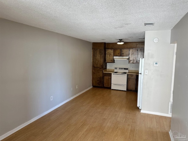 kitchen with light wood-type flooring, white appliances, a textured ceiling, and dark brown cabinetry