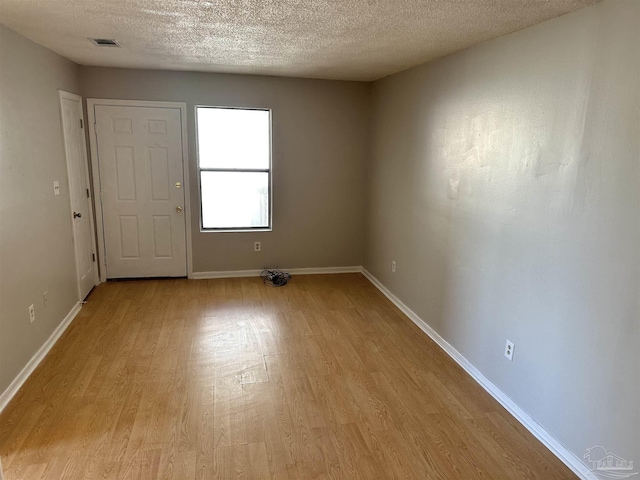 unfurnished room featuring a textured ceiling and light hardwood / wood-style flooring