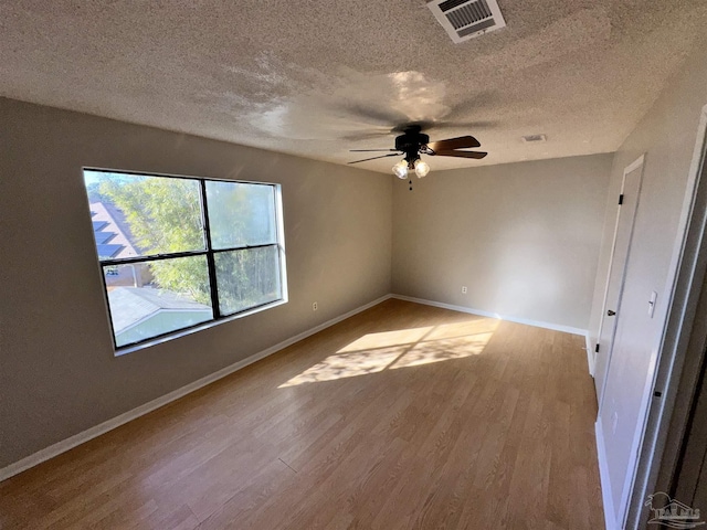 empty room with ceiling fan, a textured ceiling, and light hardwood / wood-style flooring