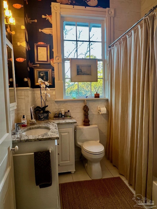 bathroom featuring a shower with shower curtain, toilet, tile patterned floors, vanity, and tile walls