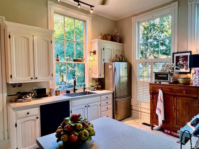 kitchen featuring white cabinetry, light countertops, a sink, and freestanding refrigerator