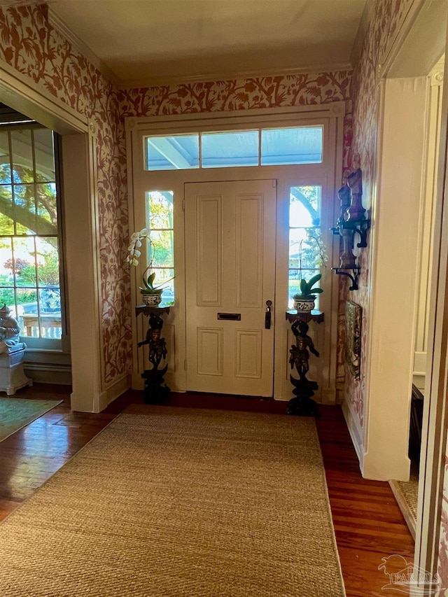 foyer with wallpapered walls, baseboards, dark wood-style flooring, and ornamental molding