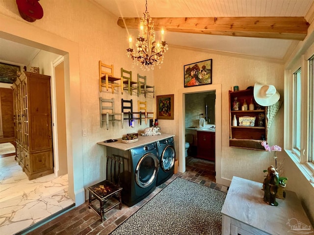 laundry area with baseboards, washing machine and clothes dryer, and an inviting chandelier