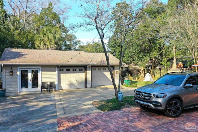 exterior space featuring roof with shingles, a detached garage, and french doors