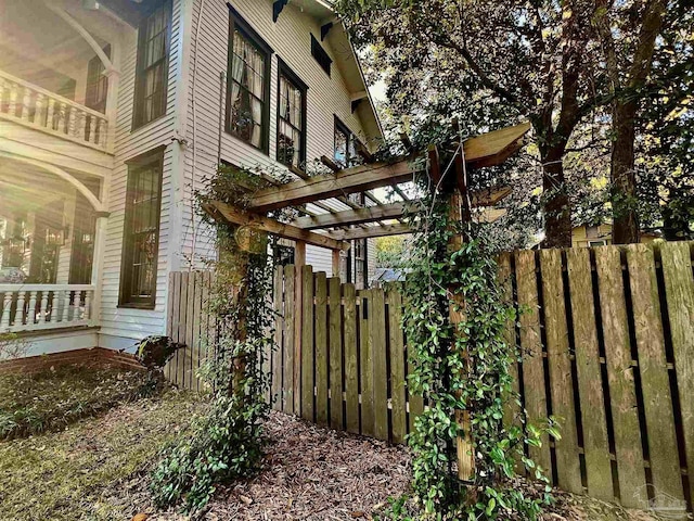 view of side of home with fence and a pergola