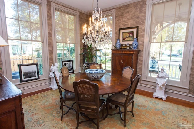 dining space with crown molding, a fireplace, baseboards, light wood-type flooring, and an inviting chandelier
