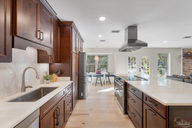 kitchen featuring french doors, ventilation hood, stainless steel appliances, sink, and light hardwood / wood-style flooring