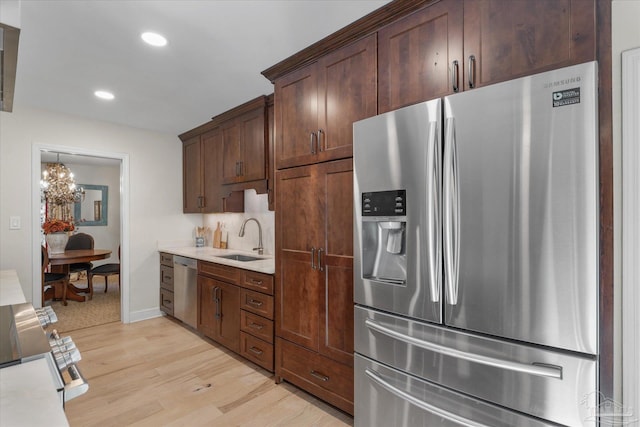 kitchen with an inviting chandelier, sink, light hardwood / wood-style flooring, appliances with stainless steel finishes, and dark brown cabinetry