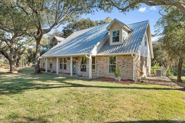 cape cod home featuring cooling unit and a front yard