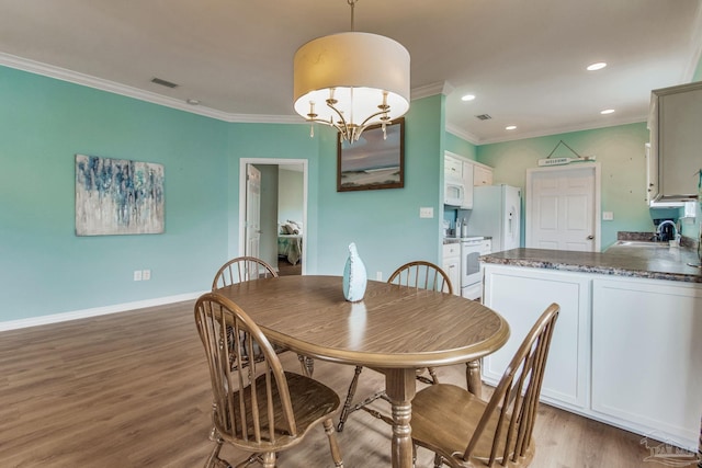 5473 Pensacola Ave, Orange Beach, AL 36561 - dining room featuring light wood finished floors, ornamental molding, recessed lighting, baseboards, and a chandelier