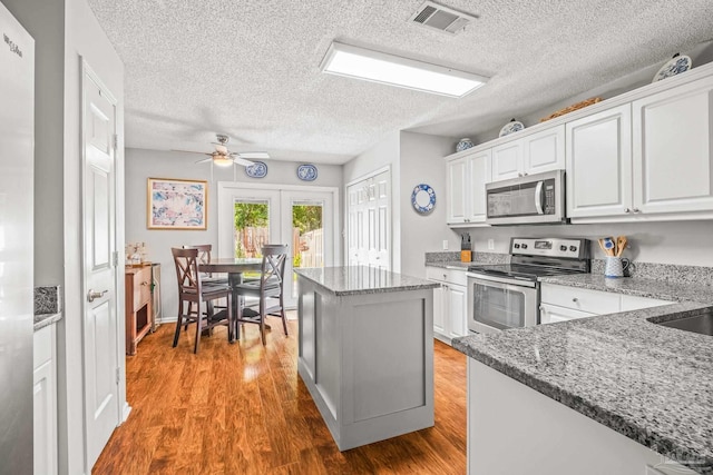 kitchen featuring a kitchen island, white cabinetry, light hardwood / wood-style floors, stainless steel appliances, and ceiling fan