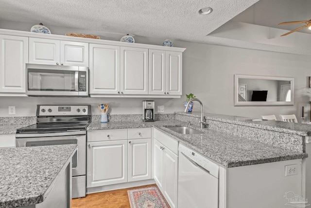 kitchen with sink, a textured ceiling, kitchen peninsula, white cabinetry, and stainless steel appliances