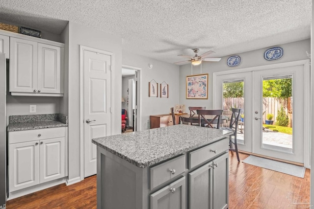 kitchen featuring french doors, dark hardwood / wood-style floors, a center island, and a textured ceiling