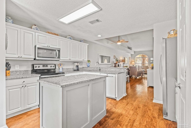 kitchen with appliances with stainless steel finishes, white cabinets, and ceiling fan