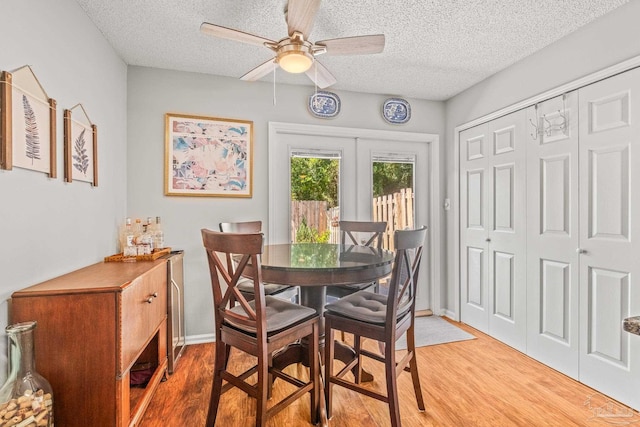 dining space with french doors, a textured ceiling, hardwood / wood-style flooring, and ceiling fan