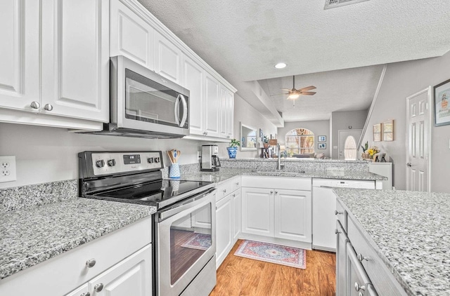 kitchen with sink, appliances with stainless steel finishes, a textured ceiling, and white cabinetry