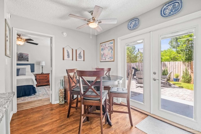 dining room featuring french doors, ceiling fan, wood-type flooring, and a textured ceiling