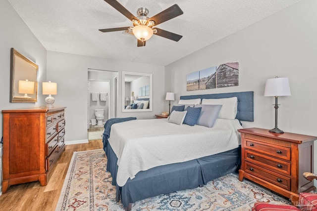 bedroom with ensuite bathroom, a textured ceiling, light hardwood / wood-style floors, and ceiling fan