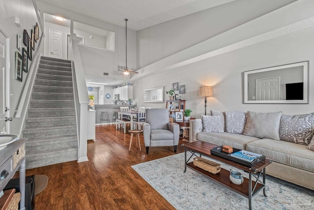 living room with dark wood-type flooring and a towering ceiling