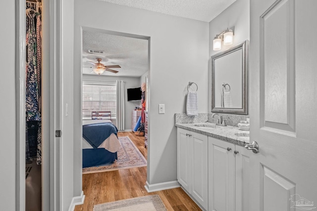 bathroom featuring vanity, hardwood / wood-style floors, a textured ceiling, and ceiling fan