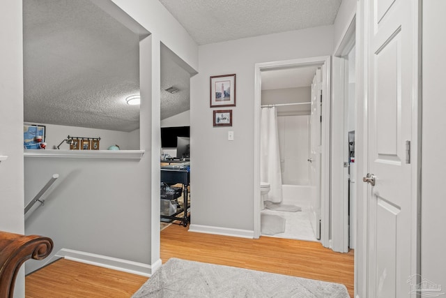 hall with a textured ceiling and hardwood / wood-style flooring