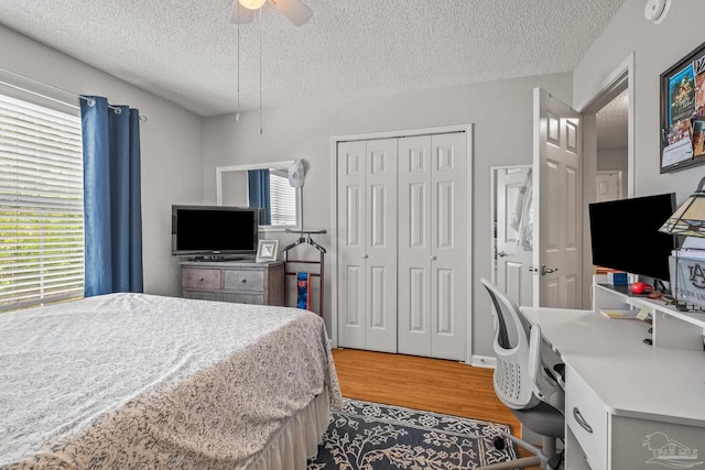 bedroom with a closet, ceiling fan, a textured ceiling, and wood-type flooring