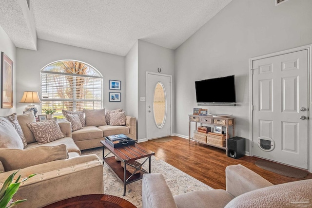 living room with a textured ceiling, hardwood / wood-style flooring, and high vaulted ceiling