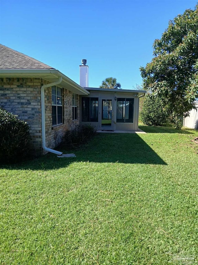 rear view of house with a yard and a sunroom